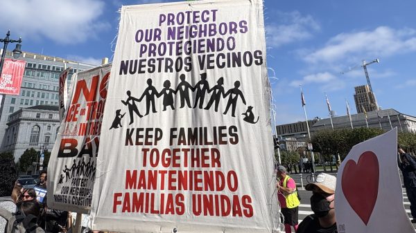 Protest sign reading "Protect our neighbors, keep families together" in English and Spanish