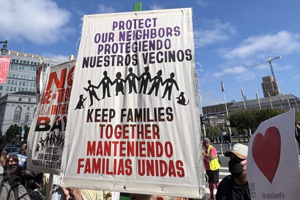 Protest sign reading "Protect our neighbors, keep families together" in English and Spanish