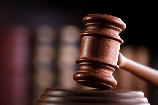 Photo of a gavel with a shelf of books in the background