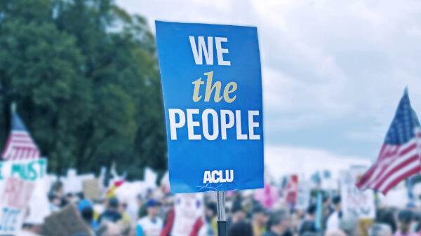 An ACLU "We the People" sign amidst an outdoor rally