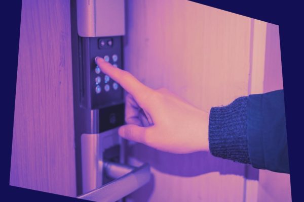 A finger presses a button on a digital door lock