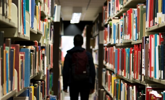 person walking between shelves of library books