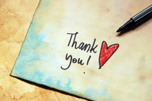 A note card with the words "Thank you!" in black ink with a red heart