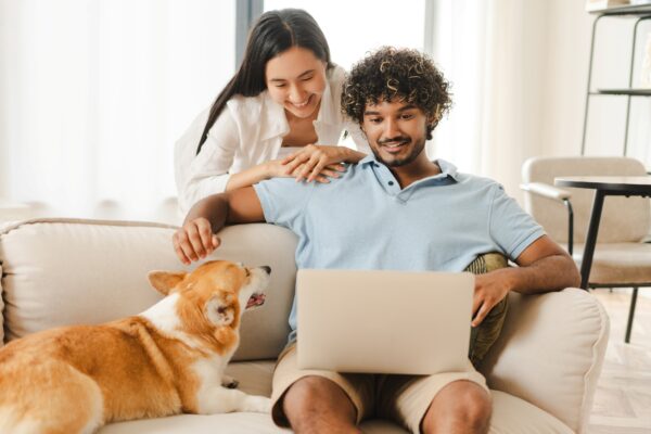 A couple with their dog looking at their laptop
