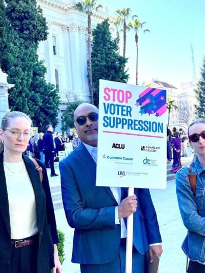 Staff from ACLU NorCal, Cal Action, and Common Cause hold signs at the Capitol saying "Stop Voter Suppression"