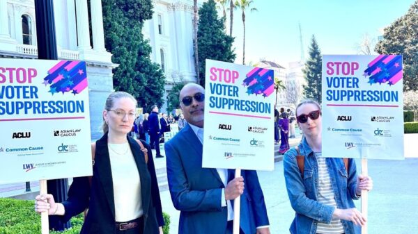 Staff from ACLU NorCal, Cal Action, and Common Cause hold signs at the Capitol saying "Stop Voter Suppression"