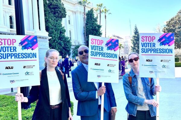 Staff from ACLU NorCal, Cal Action, and Common Cause hold signs at the Capitol saying "Stop Voter Suppression"