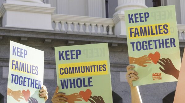 people at the CA state capitol holding signs that say "keep communities whole" and "keep families together"