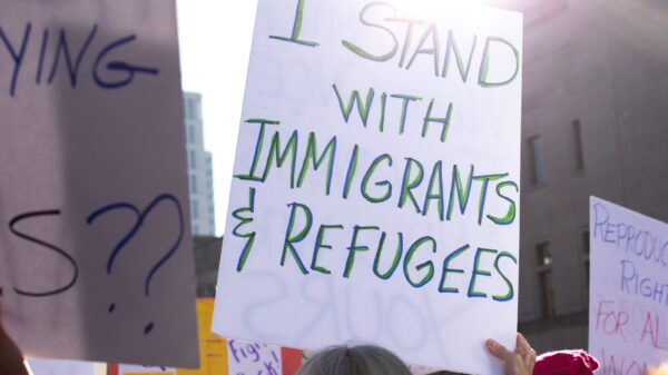 Rally crowd with sign saying "I stand with immigrants and refugees"