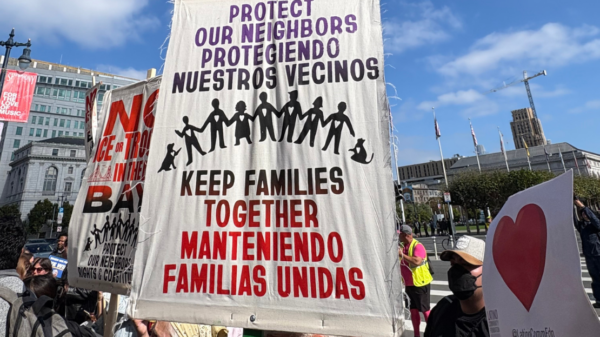 A protest sign reading, "Protect our neighbors, keep families together."