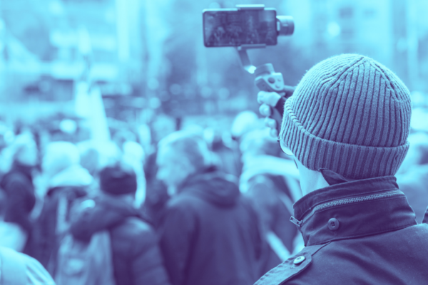Photo of a person recording cell phone video of a protest.