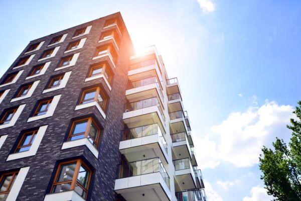 contemporary apartment building seen from below with sunny sky beyond.