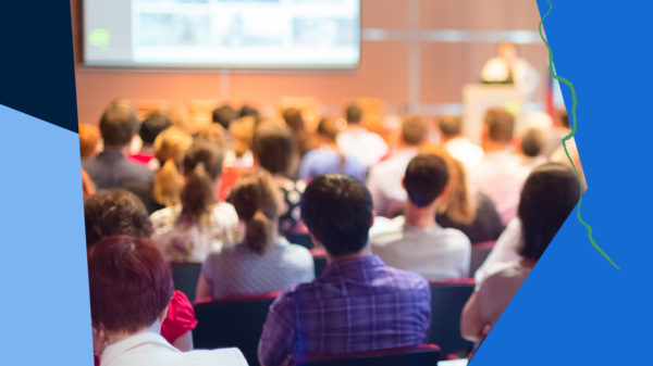 Thumbnail of a large convening of people in a lecture hall facing a presentation