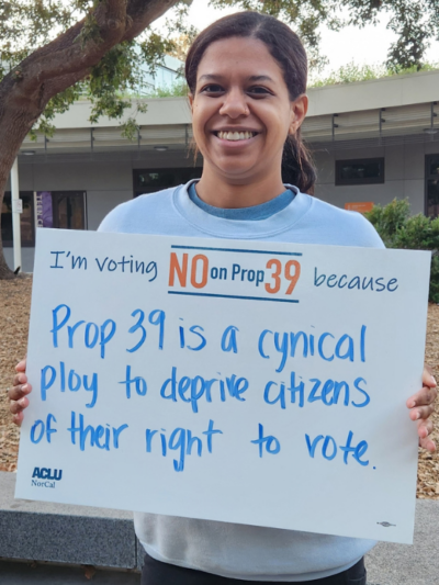 Person holding a sign that says "I'm voting No on Prop 39 because Prop 39 is a cynical ploy to deprive citizens of their right to vote.