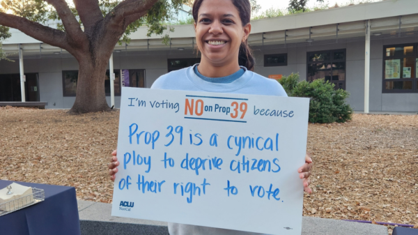 Person holding a sign that says "I'm voting No on Prop 39 because Prop 39 is a cynical ploy to deprive citizens of their right to vote.